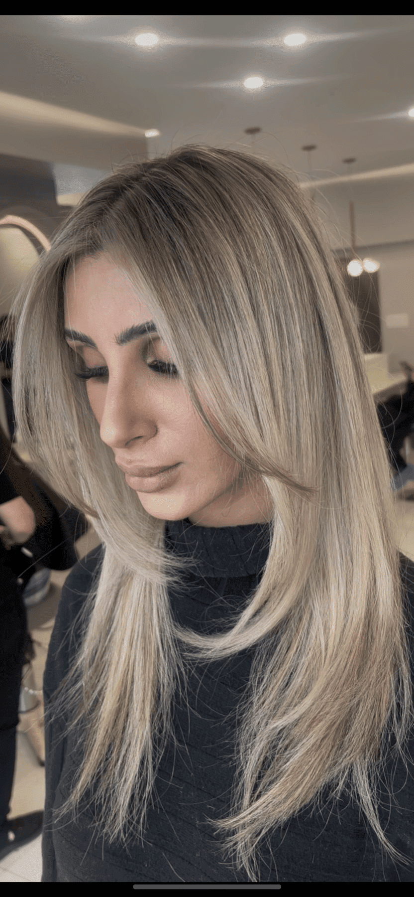 Woman with long blonde hair in a salon. Soft lighting and modern interior design in background.