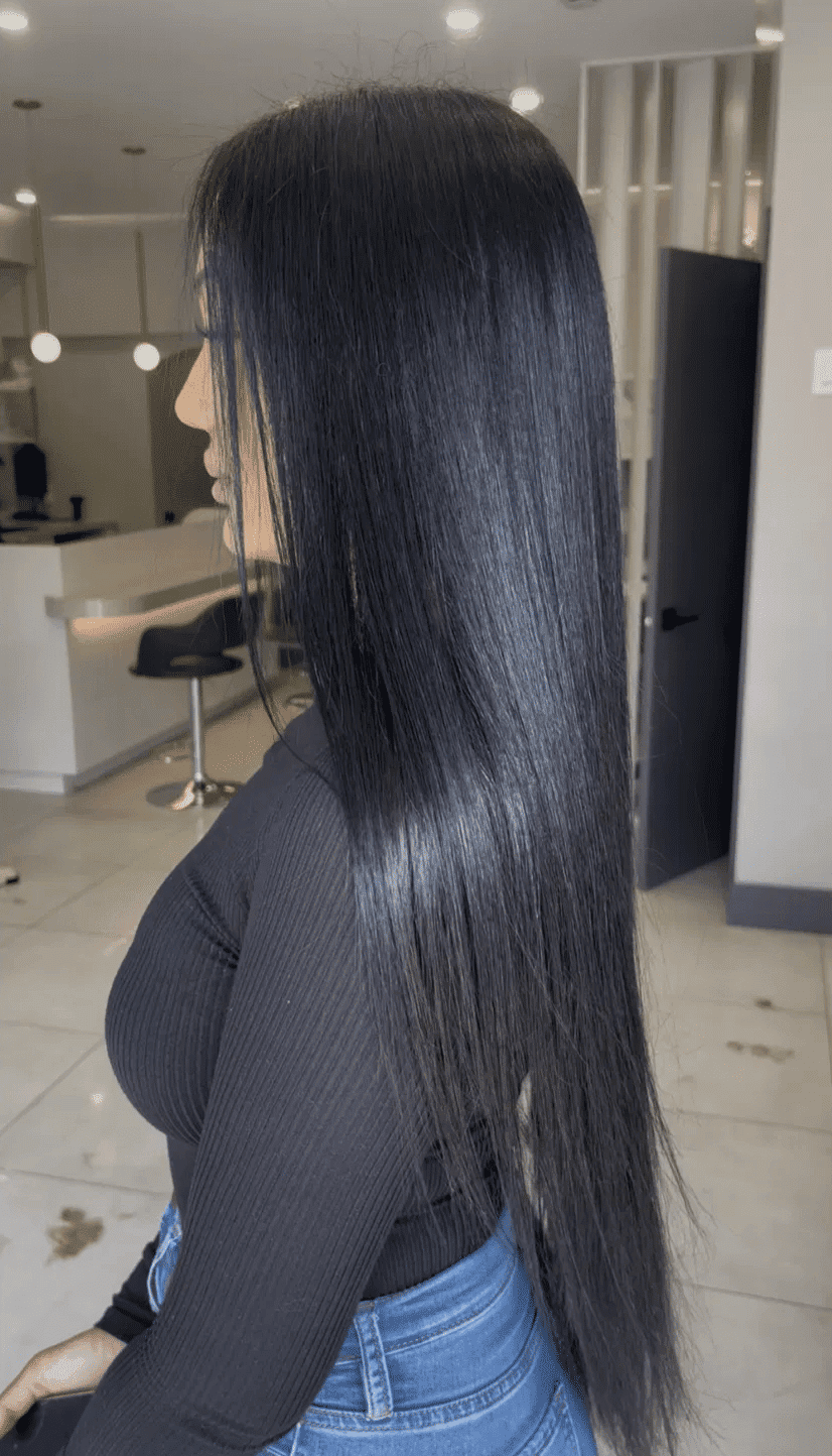 Profile view of a woman with long, straight black hair in a salon setting.