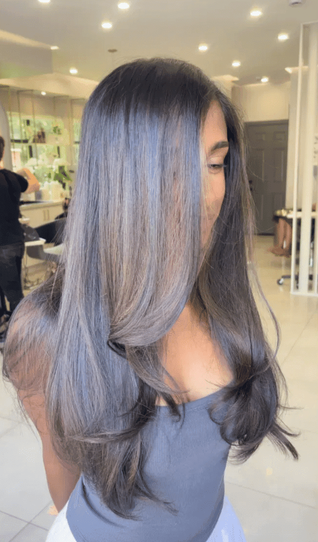 Long, silky hair with soft layers in a salon setting.